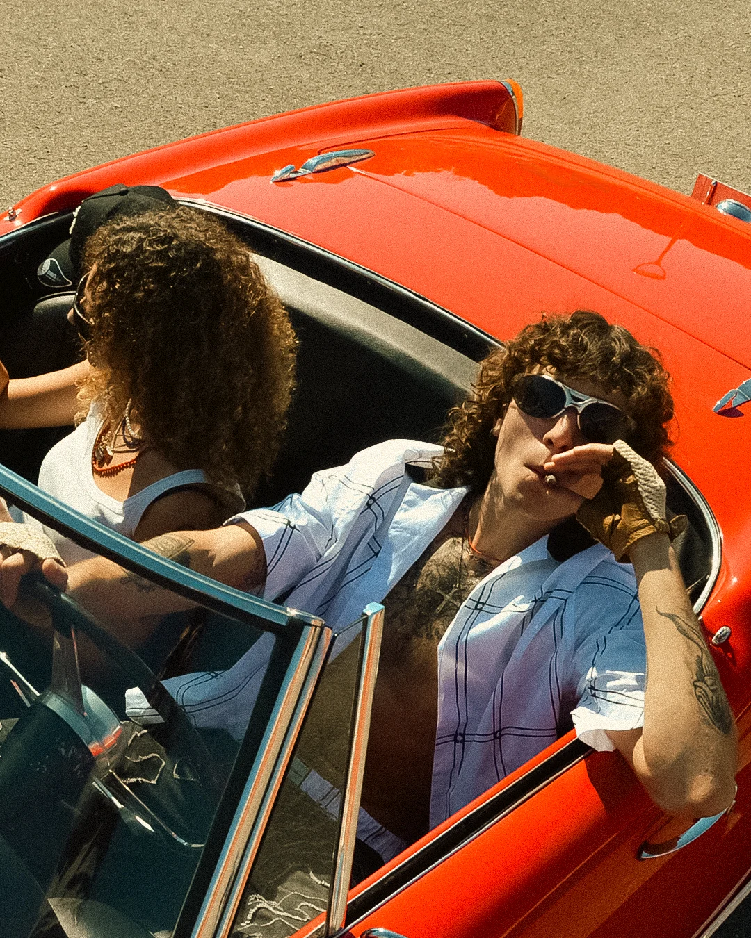 Two models inside the red roadster from the COLLAPSE campaign