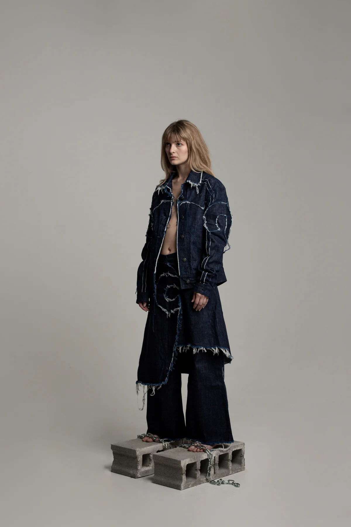 Model wearing a COLLAPSE denim set on concrete blocks