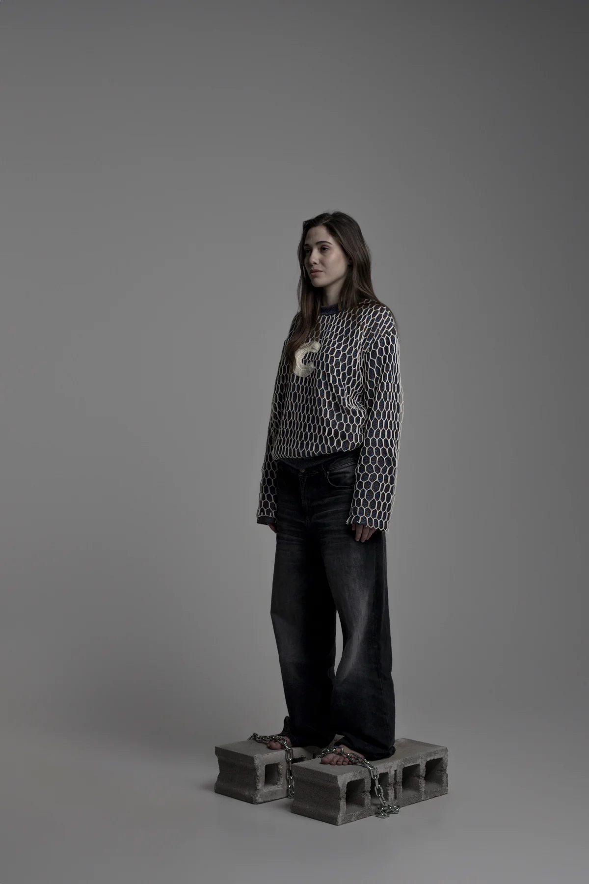 Model wearing a graphic top and dark trousers in the studio