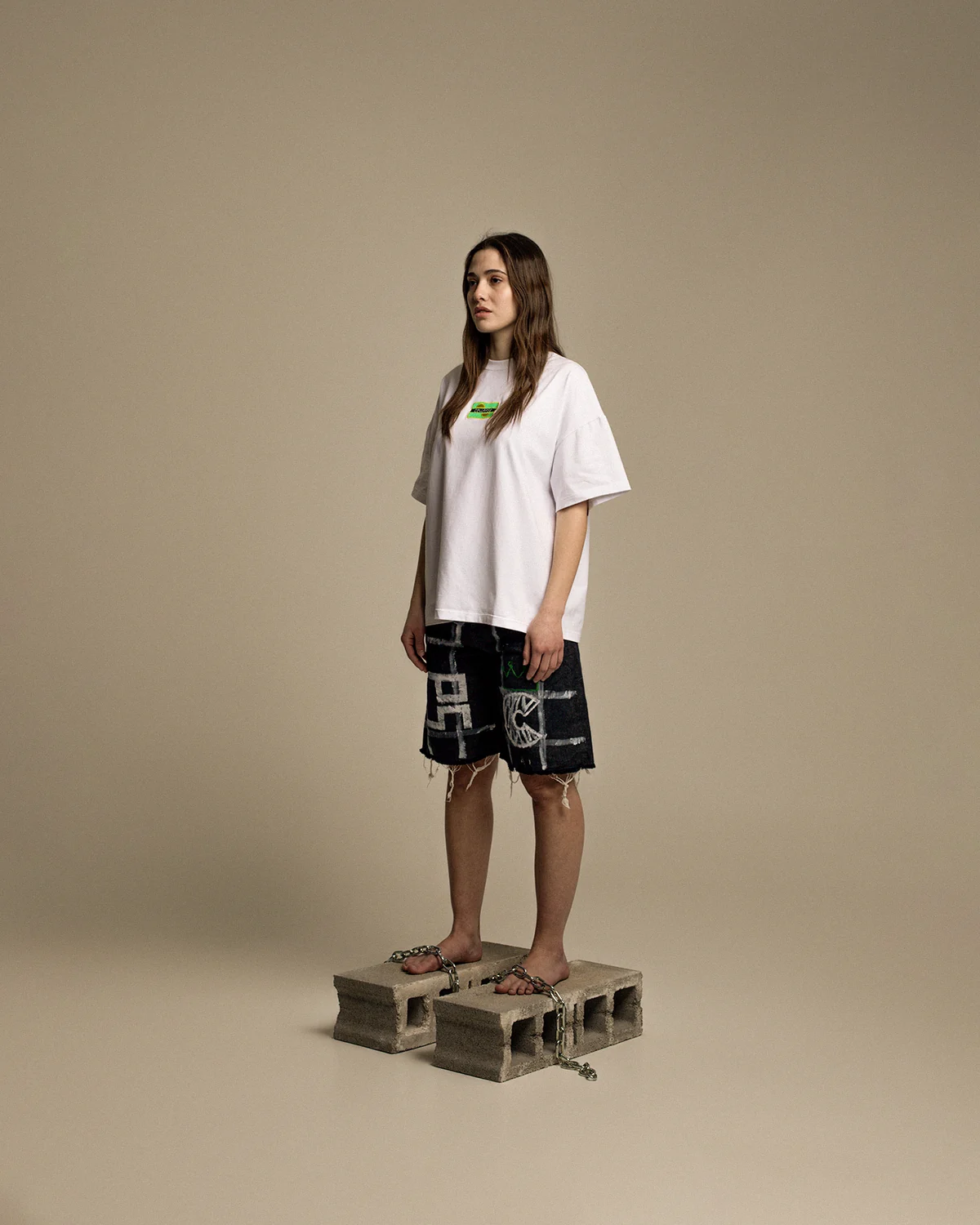 Model wearing a white T-shirt and graphic shorts on concrete blocks