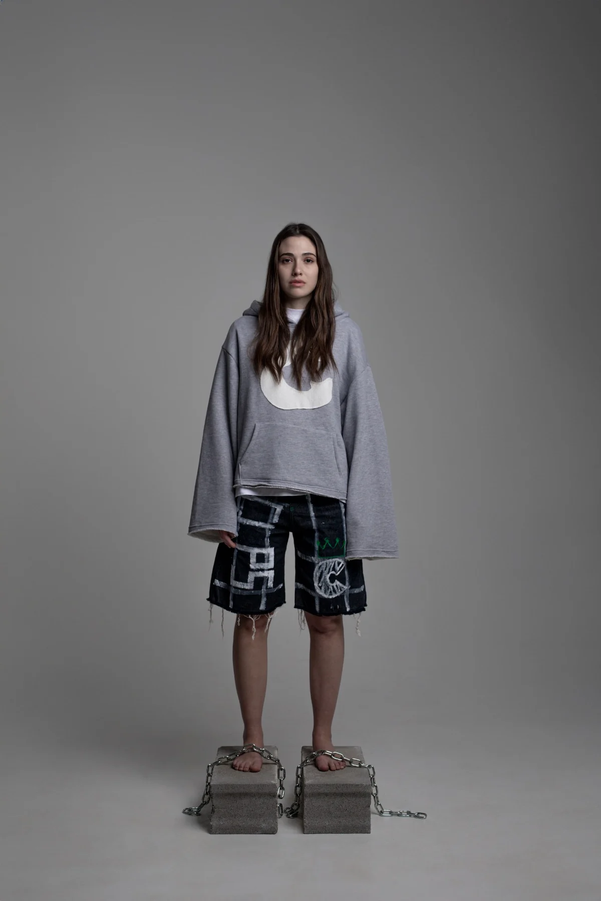 Woman wearing the grey C Logo hoodie and graphic COLLAPSE shorts, unisex look