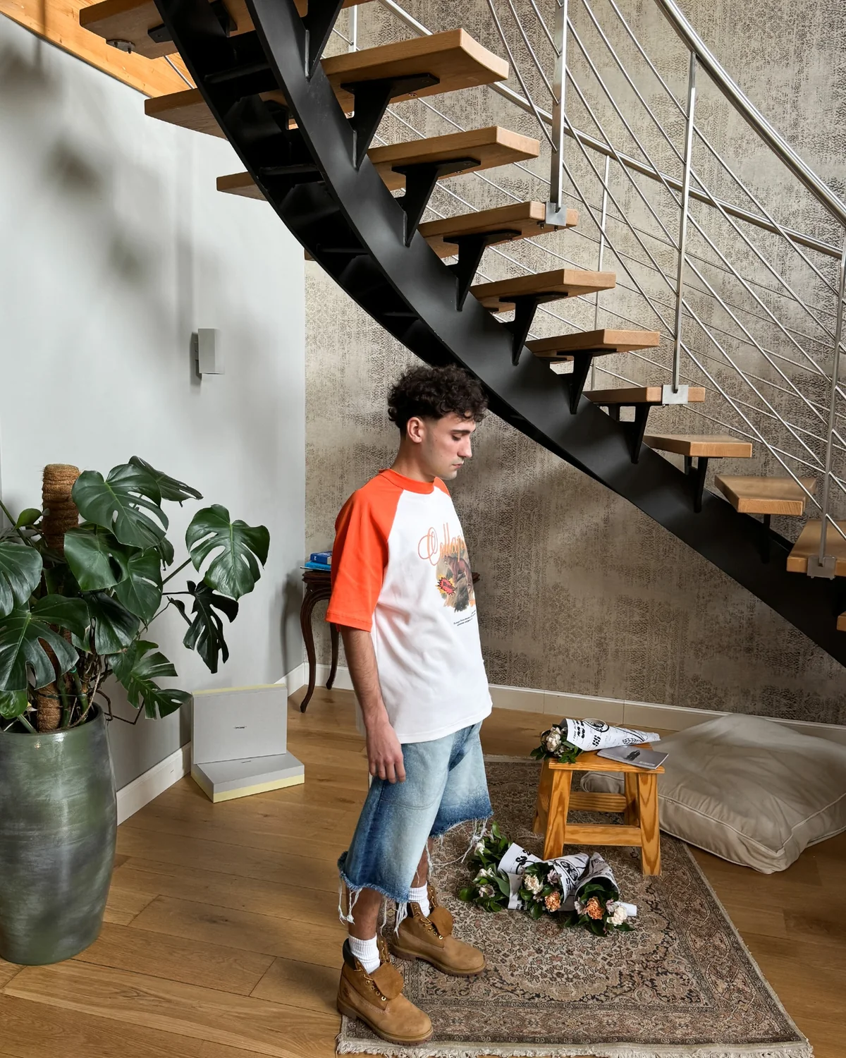 Modello con T-shirt raglan bianca e arancione e shorts in denim